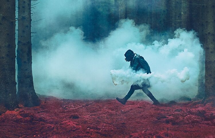 A lone figure walks through a dark, misty forest with red ground cover and thick blue smoke trailing behind. The band name “Oak” and the album title “The Third Sleep” appear in white text at the bottom.