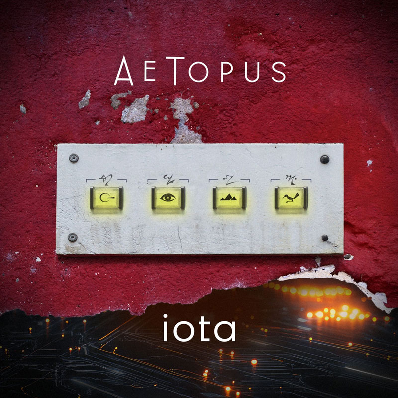 The album cover for iota by AeTopus features a textured red wall with a weathered white panel mounted on it. The panel contains four illuminated buttons, each adorned with a cryptic symbol— a looped arrow, an eye, a mountain range, and a bird in flight. Above, the artist's name, AeTopus, is displayed in a sleek, modern font, while the album title, iota, is placed below against a dark background with glowing city lights and streaks of motion.