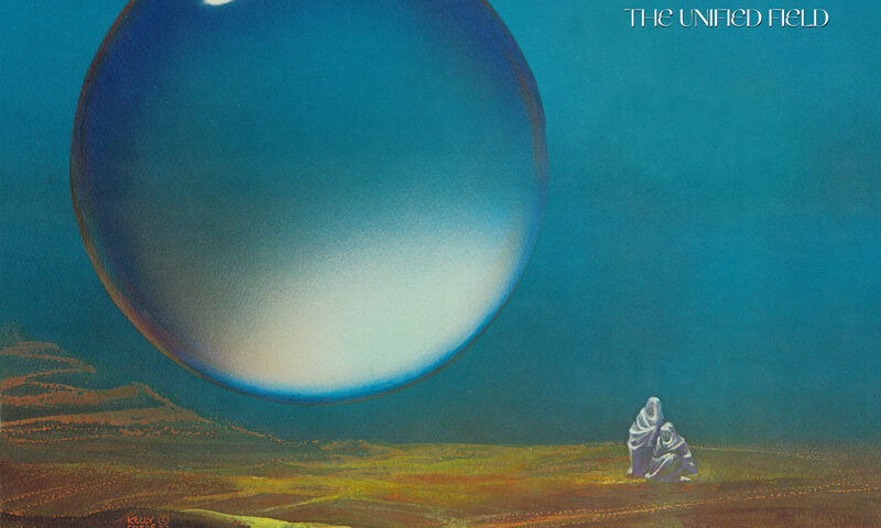 The album cover for The Unified Field by All India Radio features a landscape under a deep blue sky, dominated by a massive, reflective sphere hovering above the ground. Two small, robed figures stand below it, gazing upward. The band’s name and title appear in the upper right corner.