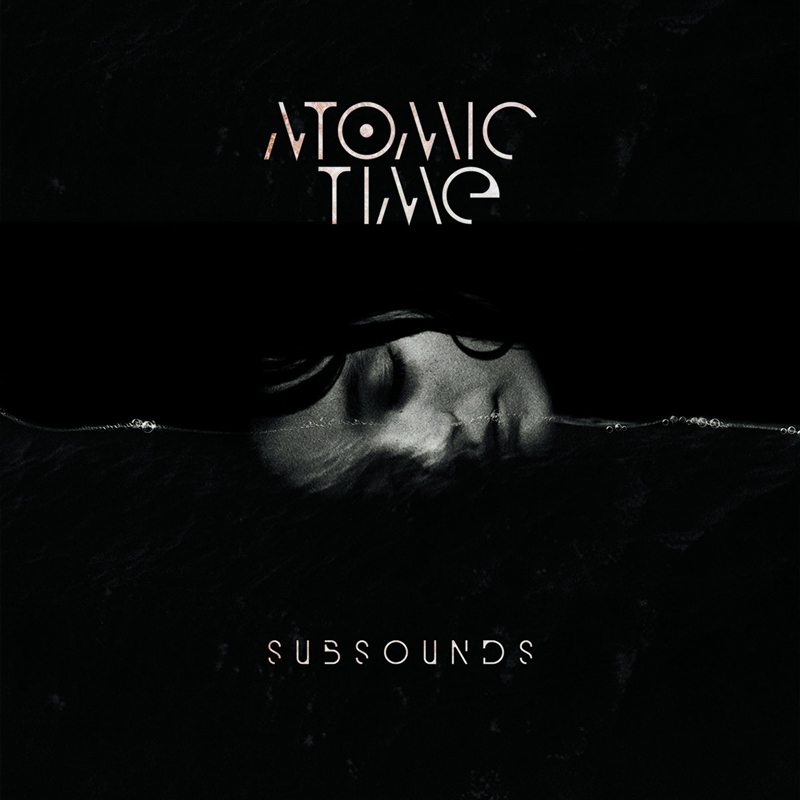 The album cover for Subsounds by Atomic Time features a grayscale image of a woman's face floats partially submerged in dark water. The band's name, "Atomic Time," appears at the top in fragmented typography, while the album title, "Subsounds," sits below in a futuristic font.
