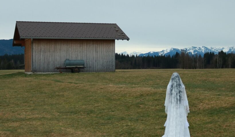 Coma Rossi – "Void cover artwork. a photo of the bavk of a woman in a wedding gown looking towards a barn and distant snow capped mountains.