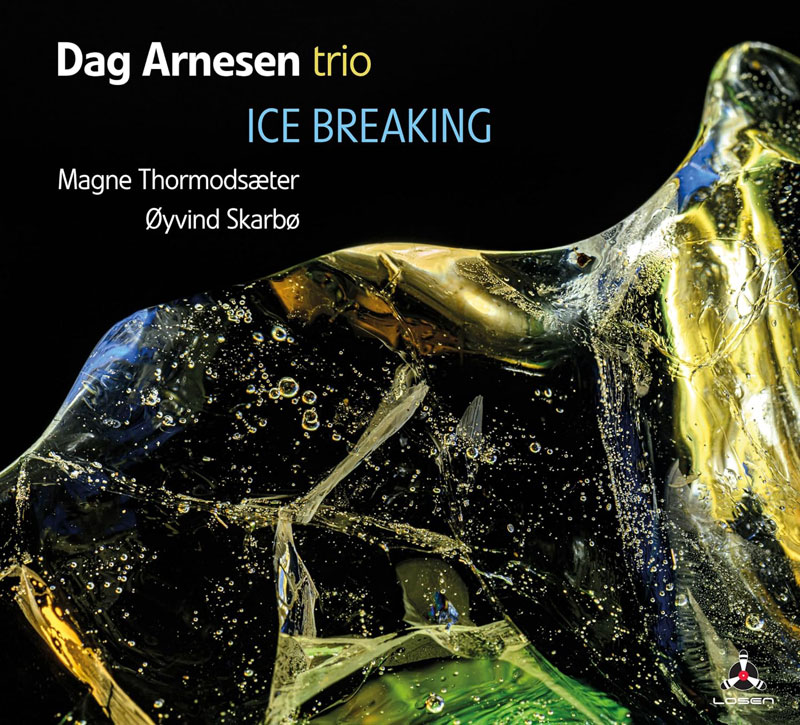 The album cover for Ice Breaking by the Dag Arnesen Trio features a close-up of a fractured ice formation, illuminated by golden and blue reflections against a deep black background. The typography is clean and modern, with "Ice Breaking" in a cool blue hue. The names of bassist Magne Thormodsæter and drummer Øyvind Skarbø appear beneath the title, while the Losen Records logo sits subtly in the corner.