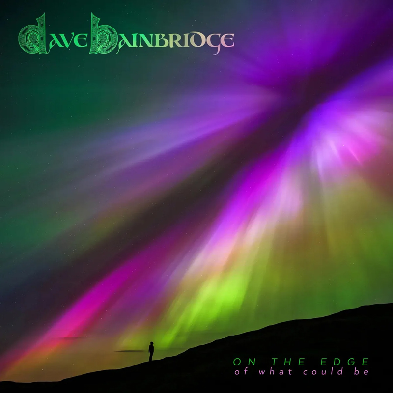 The cover of On The Edge (Of What Could Be) by Dave Bainbridge features a lone silhouette standing on a ridge beneath an aurora. Vivid streaks of purple, green, and pink light radiate across the night sky, converging in a burst of color. The artist’s name appears in ornate green lettering at the top left, while the album title rests at the bottom right in modern type.