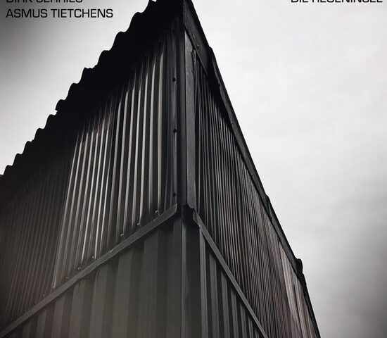 Dirk Serries and Asmus Tietchens - Die Regeninsel cover artwork. The cover of Die Regeninsel features an upward-looking photograph of a corrugated metal structure shot from a corner angle. The artists' names appear in the upper left corner, while the album title sits opposite in the upper right.