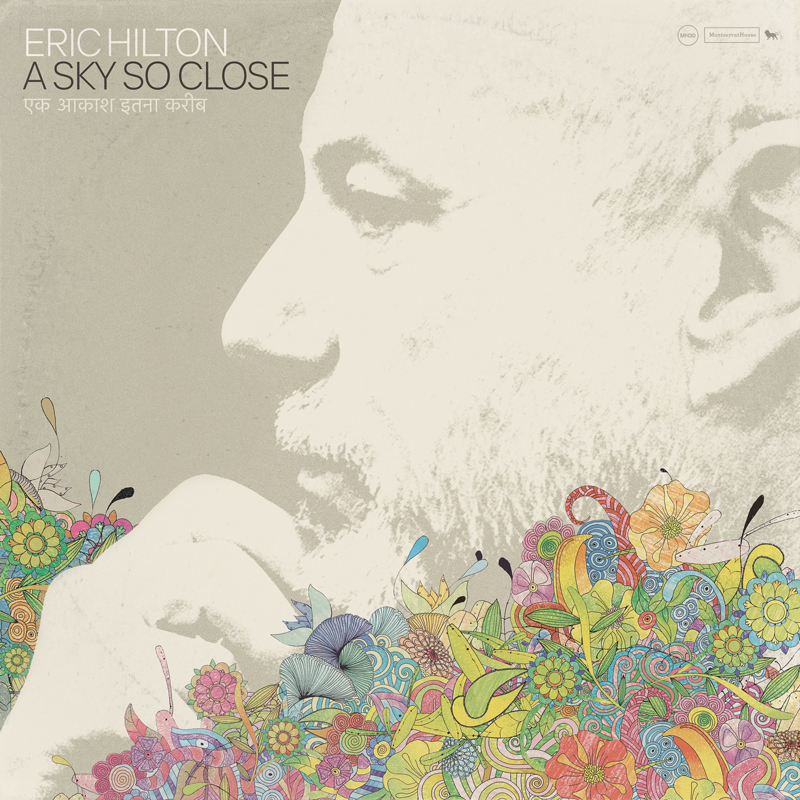 A grayscale profile of a bearded man, Eric Hilton, dominates the cover, his face rendered with soft contrast against a cream background. The lower portion erupts in colorful hand-drawn flowers, leaves, and abstract forms. The title A Sky So Close and the artist name Eric Hilton appear in modern type near the top, with Hindi script beneath the title.