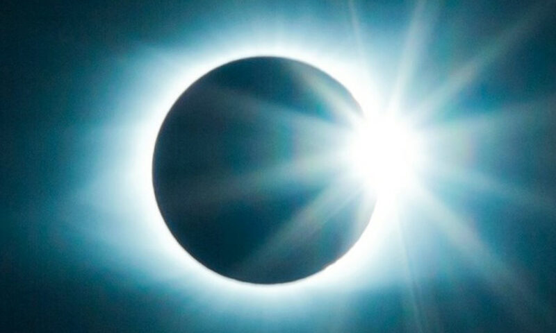 The High Orbit album cover shows a solar eclipse, with the sun’s radiant light flaring from behind the moon against a deep blue-black sky. The band name “Head Spin” and album title “High Orbit” appear in yellow lettering, positioned in the upper right and lower left corners.