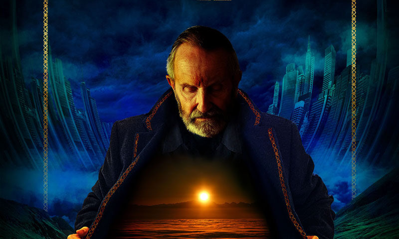 IQ's Dominion album cover features at the center an older man with a stern expression and a trimmed beard. He opens his dark, ornate coat to reveal a glowing scene within—a vast, otherworldly landscape illuminated by a golden sunset over a sea of clouds. The background contrasts futuristic cityscapes with ominous stormy skies. The band's logo appears at the top in gold, while the album title, Dominion, is subtly placed within the illuminated scene on his chest.