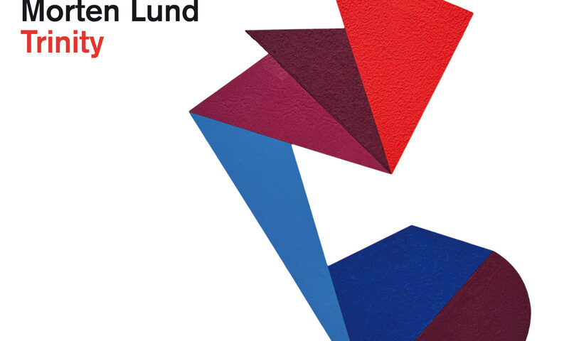 The album cover for Trinity features a geometric design. Shapes in red, burgundy, blue, and purple overlap and connect, forming a figure against a white background. The musicians’ names, iiro Rantala, Kaisa Mäensivu, and Morten Lund, appear in black text at the top left, with the album title Trinity highlighted in red. Logos for ACT and Château Palmer are placed in the lower left corner.