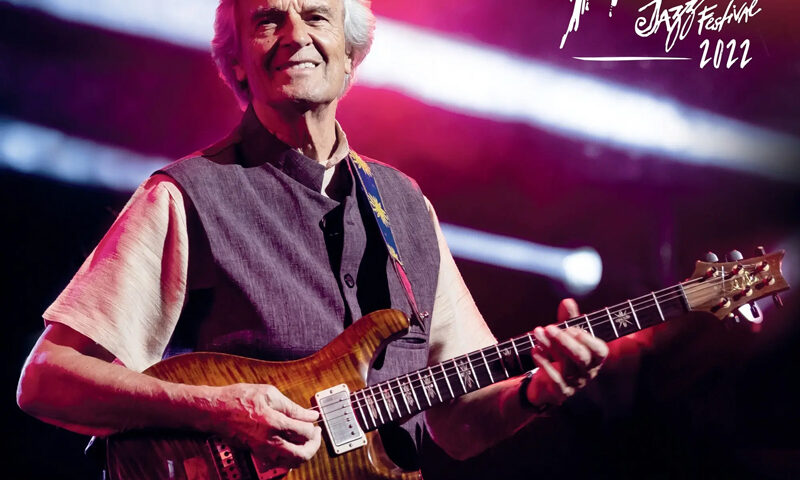 John McLaughlin and The 4th Dimension - Live at the Montreux Jazz Festival 2022 cover artwork. A photo of John performing live, playing his electric guitar.
