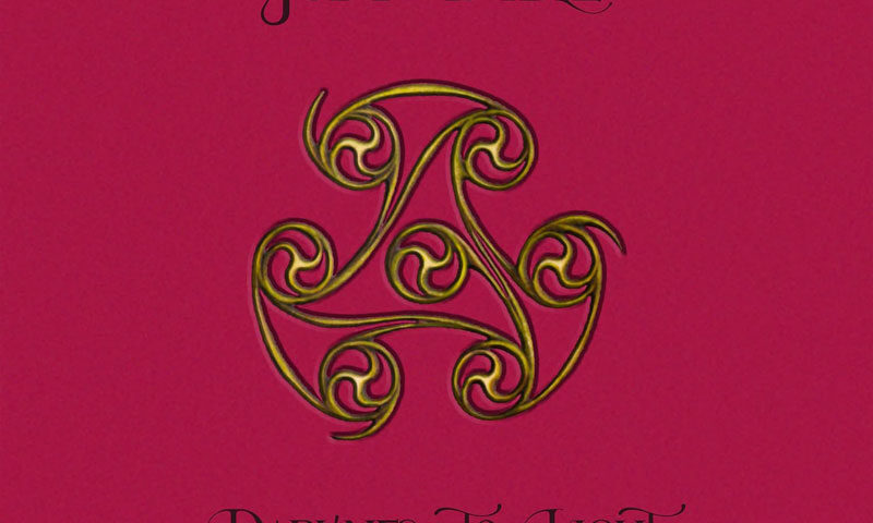 The album cover for Judy Dyble – Darkness to Light: The Recordings 2004–2006 features a rich magenta background with elegant, calligraphic black text. At the center is a gold and green Celtic-inspired triskelion symbol.