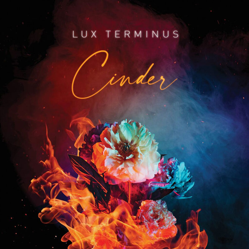 The cover of Cinder by Lux Terminus features a bouquet of vividly colored flowers engulfed in flames, set against a smoky, gradient background that shifts from deep red to blue. The album title is written in elegant, glowing script, while the band name appears above in sleek, modern sans-serif type.