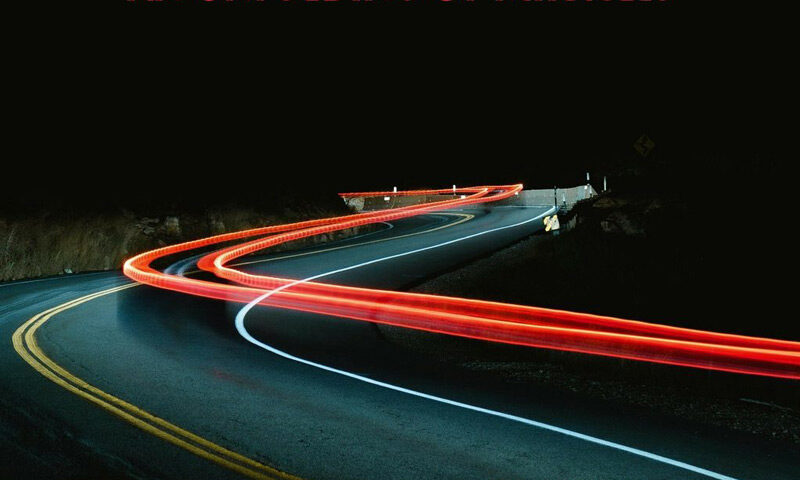 Nick Fletcher – An Unfolding of Miracles cover artwork. The album cover for An Unfolding of Miracles by Nick Fletcher features a winding mountain road at night, illuminated by red light trails from a passing vehicle.
