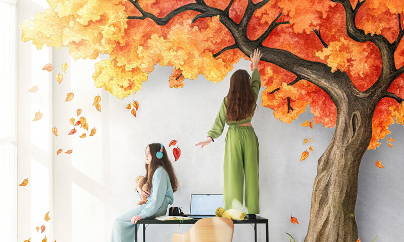 The album cover shows two women in a bright room interacting with a large, vividly painted autumn tree that appears to grow from the wall and floor. One stands on a desk reaching toward the orange and gold leaves, while the other sits holding a teddy bear.