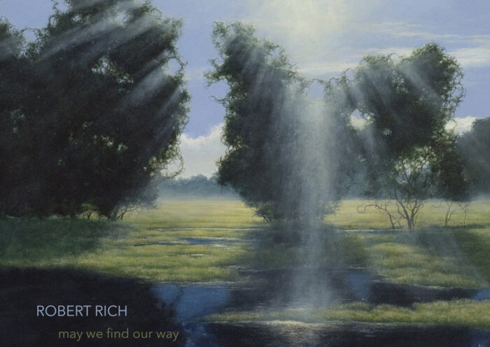 The album cover for May We Find Our Way by Robert Rich features a landscape where sunlight breaks through a stand of trees, casting rays onto a grassy field. Below, a reflective body of water mirrors the sky and trees, subtly revealing a starry expanse. The title and artist name are understated, set in lowercase text.