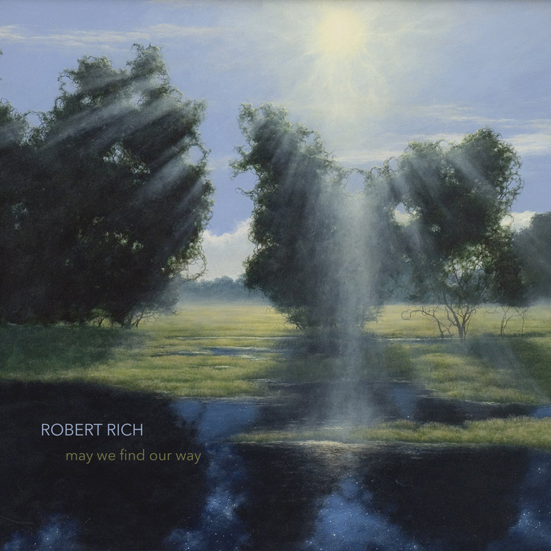 The album cover for May We Find Our Way by Robert Rich features a landscape where sunlight breaks through a stand of trees, casting rays onto a grassy field. Below, a reflective body of water mirrors the sky and trees, subtly revealing a starry expanse. The title and artist name are understated, set in lowercase text.