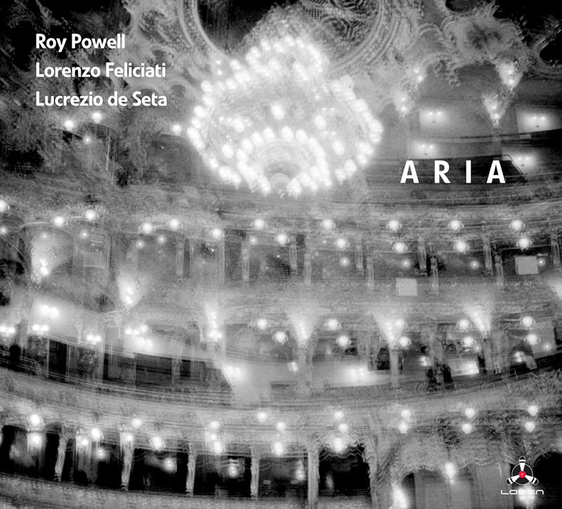 Roy Powell Aria cover artwork. A black and white, out of focus photo of a concert hall with a chandelier in the middle.
