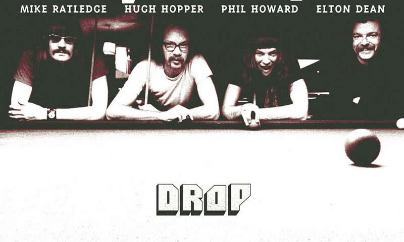The album cover for Drop (Remastered) by Soft Machine features a black-and-white photo of the band members—Mike Ratledge, Hugh Hopper, Phil Howard, and Elton Dean—leaning over a pool table. The band's name appears at the top in bold lettering, with each member's name below it. The title Drop is centered in a minimalist font, while a red "Remastered" stamp appears below.