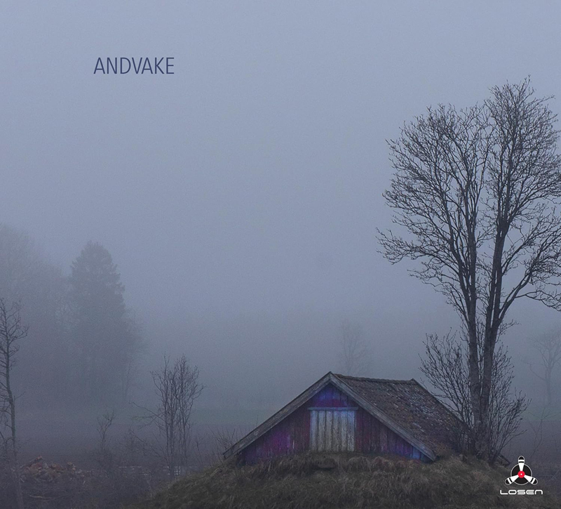 Andvake presents a fog-drenched rural scene with a small weathered shed in muted purples and browns at the center. Bare trees rise around it.