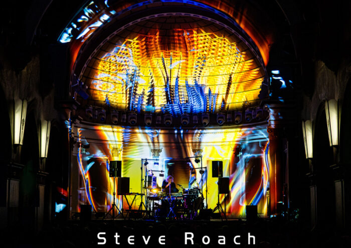 Steve Roach La Rosa cover artwork. A live image of Roach on stage with multiple colors of light.