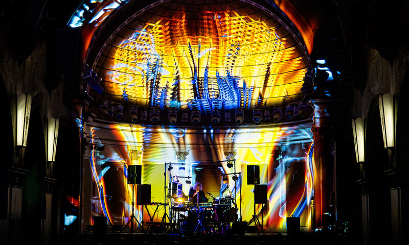 Steve Roach La Rosa cover artwork. A live image of Roach on stage with multiple colors of light.