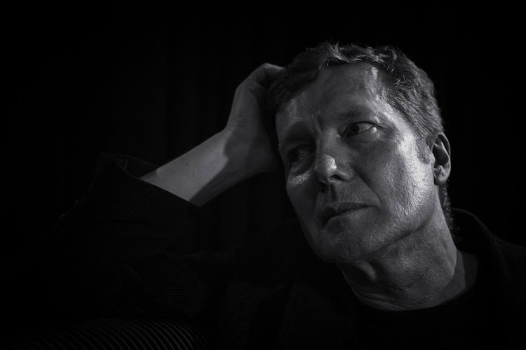 Tim Bowness - photo by Leon Barker. Black and white of the artist leaning on his right hand.