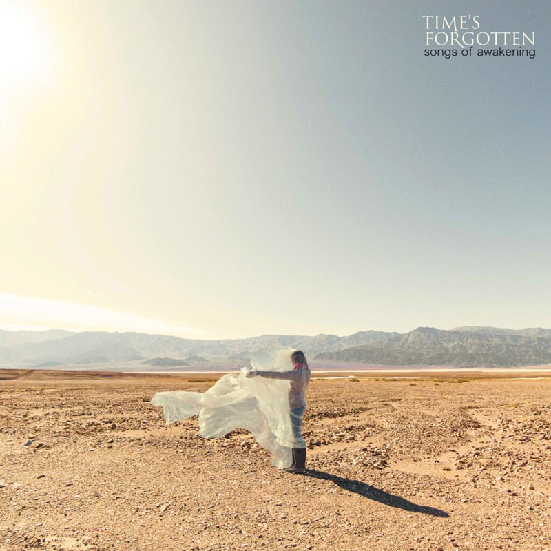 Time’s Forgotten – “Songs of Awakening” cover atwork. a photo of a woman standing in a flat desertlike zone holding flowing white cloth.