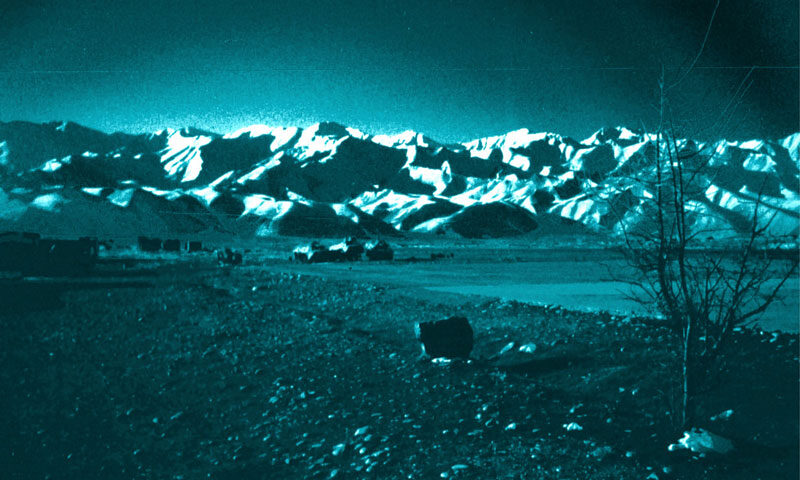 Volker Lankow - Abandoned Land cover artwork. a blue colored photo of an Afghan landscape with rocky terrain and a large mountain range in the background.