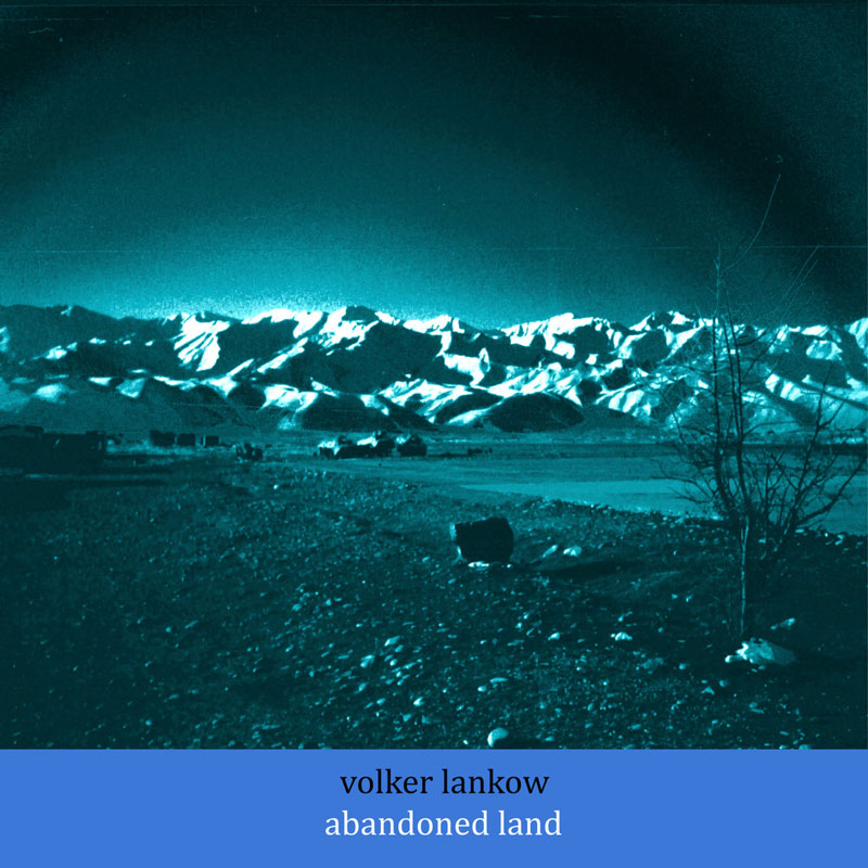 Volker Lankow - Abandoned Land cover artwork. a blue colored photo of an Afghan landscape with rocky terrain and a large mountain range in the background.