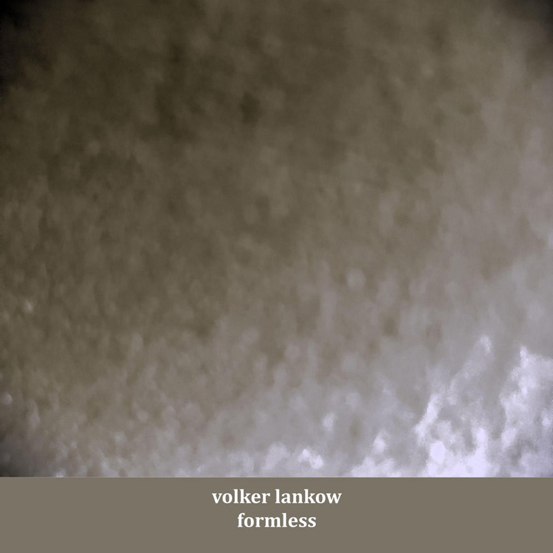 The cover of Formless by Volker Lankow features a blurred surface in muted gray tones, creating a grainy effect. At the bottom, a taupe strip carries the artist’s name and album title in simple white lowercase text.