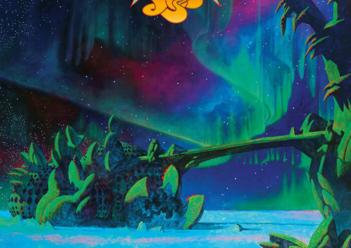 The cover of Aurora by Yes features an otherworldly landscape illuminated by brilliant green, turquoise, blue, and purple northern lights. Strange, spiky alien vegetation surrounds a luminous icy expanse beneath a star-filled sky. A twisted tree branch stretches across the scene, while the band's ornate red-and-yellow logo floats near the top.