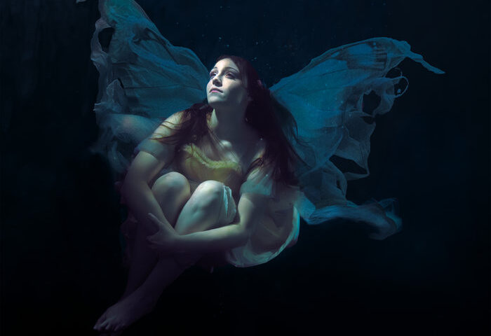 Maiah Wynne Out of the Dark cover artwork. A photo of the artist wearing a flowing dress looking up.