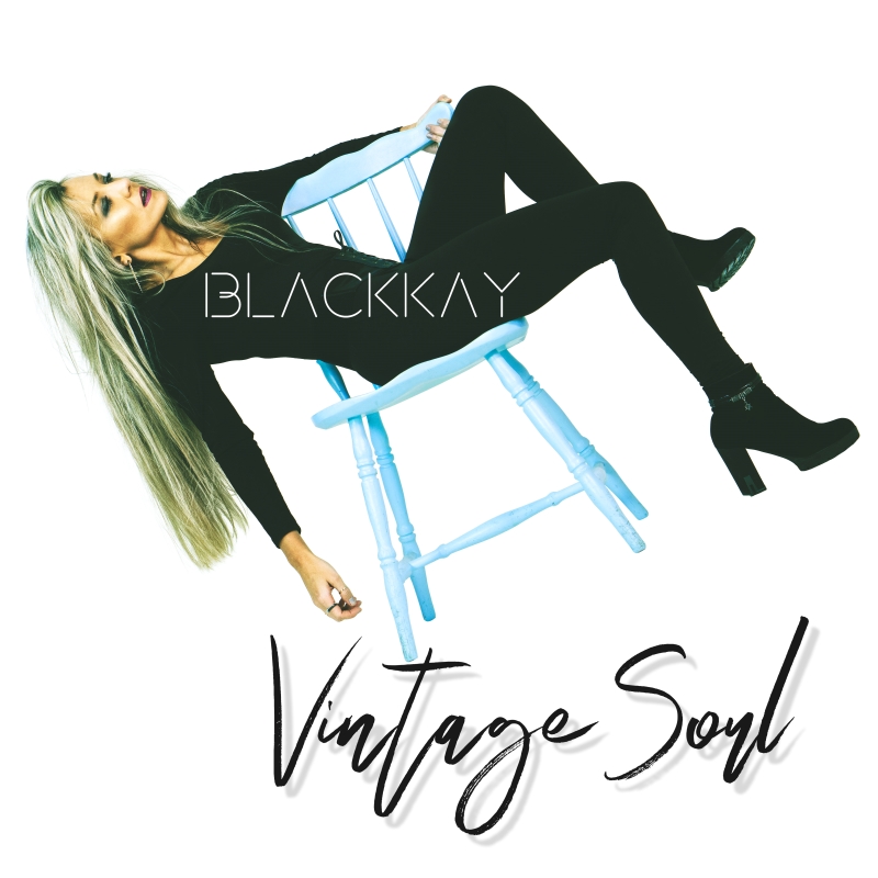 The cover of Vintage Soul by Blackkay shows a woman in a black outfit reclining sideways on a pale blue wooden chair against a white background. The artist’s name appears in modern lettering across her body, while the album title is written below in handwritten-style script.